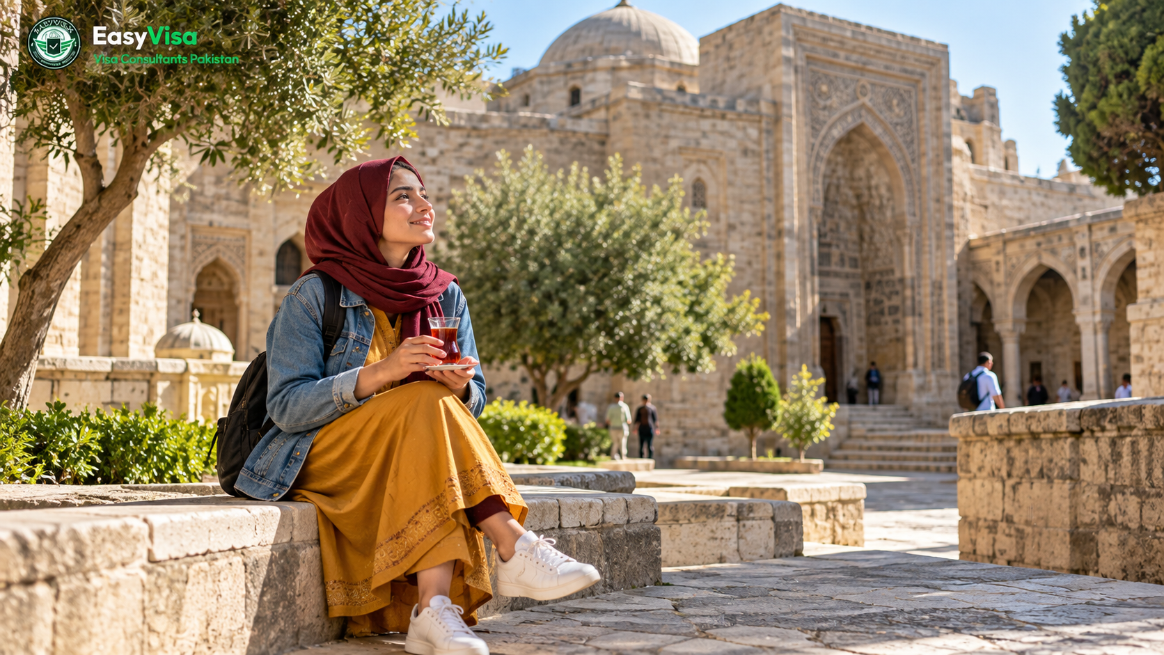Young Pakistani woman traveller drinking tea in a pear-shaped glass in the stone courtyard of the Shirvanshahs Palace in Baku