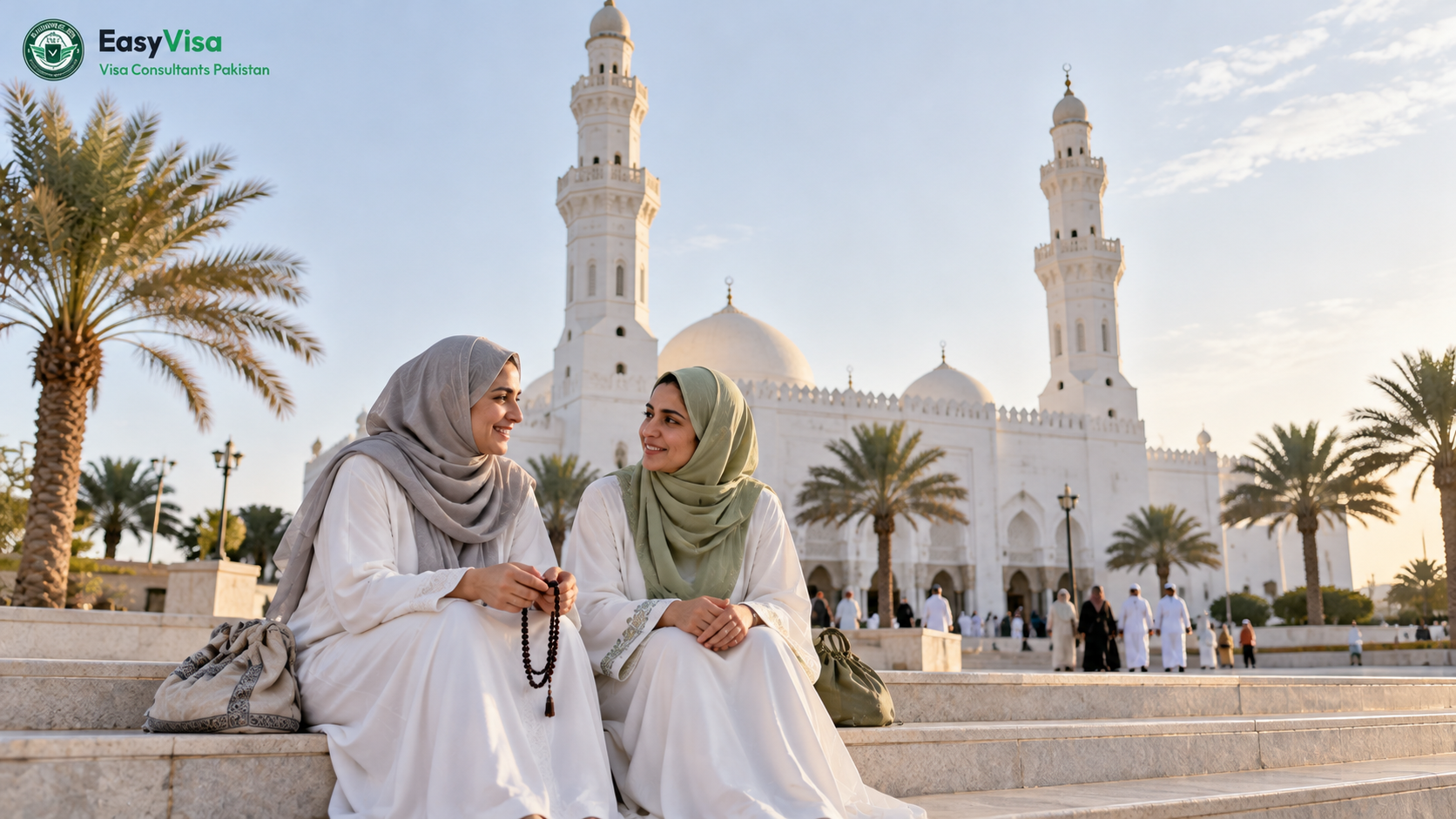Two Pakistani women pilgrims resting on the steps outside Masjid al-Qiblatayn in Madinah in soft morning light